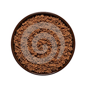 Cane brown muscovado sugar in a bowl isolated on white background. Top view. Indian sugar