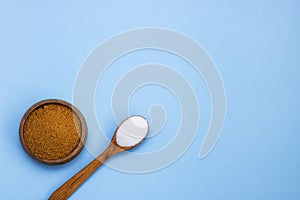 cane brown sugar in a wooden bowl white crystalline sugar in a wooden spoon on a blue background with copy space