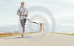 Canicross exercises. Female runs with his beagle dog and happy smiling. Autumn spring outdoor sport activity photo