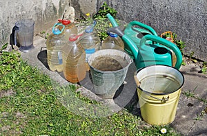 Canisters, buckets and watering cans with water are found near t