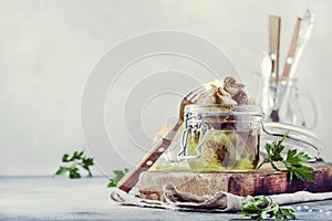 Canned artichokes in olive oil, in glass jar with fork, gray kitchen table background, selective focus