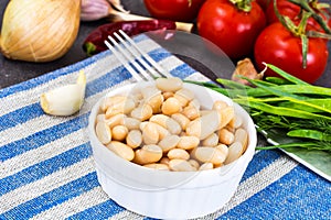 Canned beans with olive oil and garlic in white salad bowl