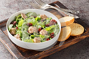 Canned cod liver salad with fresh arugula and sun-dried tomatoes served with toast close-up in a bowl. Horizontal