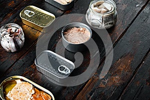 Canned fish with different assortment types of seafood, on old dark  wooden table background., with copyspace  and space for text