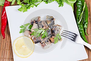 Canned fish on dish among vegetables and greens, top view