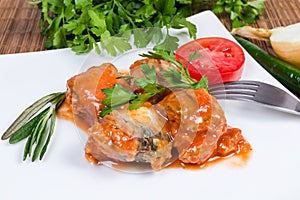 Canned fish in tomato sauce on dish, greens and vegetables