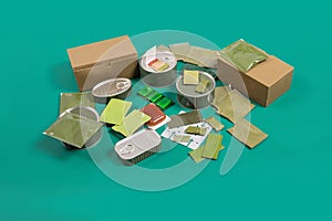 Canned food set and terrines with survival accessories on green background.