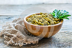 Canned green peas in a wooden bowl.