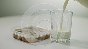 Canned herring on table with white milk pouring in glass. Close-up incompatible food and drink indoors.