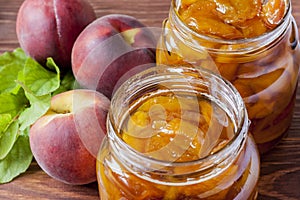 Canned jars of homemade peach jam on a wooden table in the morning sun. The concept of home-made preservation. Close up