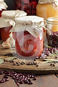 Canned kidney bean in tomato paste in glass plastic free jar on rustic table, closeup, canned produce concept