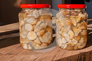 Canned mushrooms boletus in glass jars on wooden table