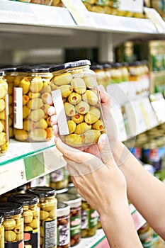 Canned olives in hands buyer in shop