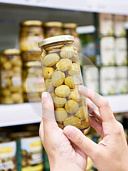 Canned olives in hands buyer in shop