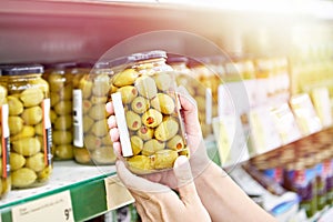 Canned olives in hands buyer in shop