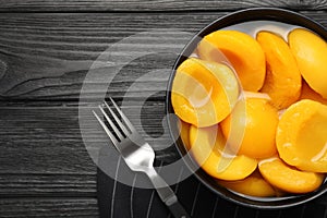 Canned peach halves on black wooden table, flat lay. Space for text