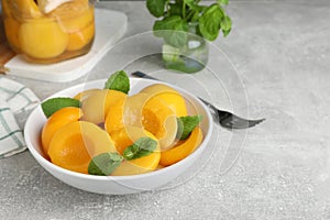 Canned peach halves in bowl on light table, space for text