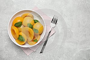 Canned peach halves and fork on light table, flat lay. Space or text