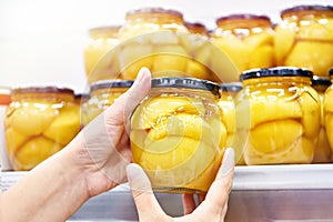 Canned peaches in glass jar in hands