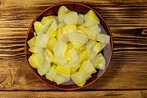 Canned pineapple pieces in ceramic plate on wooden table