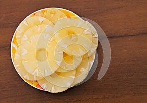 Canned pineapple on a plate on wooden table