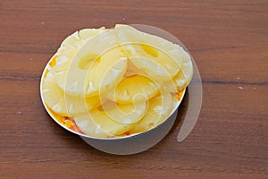 Canned pineapple on a plate on wooden table