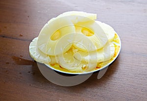 Canned pineapple on a plate on wooden table