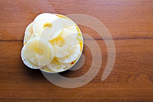 Canned pineapple on a plate on wooden table