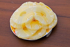 Canned pineapple on a plate on wooden table