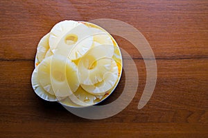 Canned pineapple on a plate on wooden table