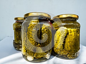 Canned and preserved fresh homemade pickles cucumbers in glass jars that has been pickled in a brine, vinegar, spices, garlic,