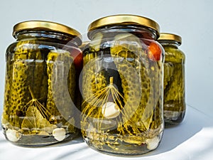 Canned and preserved fresh homemade pickles cucumbers in glass jars that has been pickled in a brine, vinegar, spices, garlic,