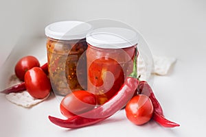 canned red peppers with tomatos in a glass jar on a white background