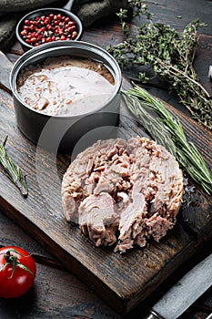 Canned soy free albacore white meat tuna, on wooden cutting board, on old dark  wooden table background. with herbs and