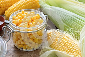 Canned sweet corn in glass jar, fresh and cooked corn cobs. photo