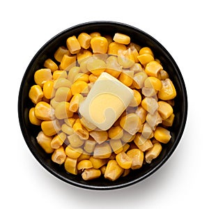 Canned sweet corn with a knob of butter in a black ceramic bowl isolated on white. Top view