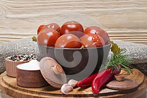 Canned tomato in a plate with spices on a wooden background