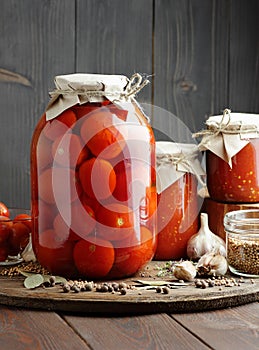 Canned tomatoes in glass jar on wooden rustic table in pantry or village kitchen, closeup