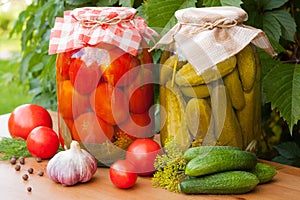 Canned Tomatoes And Pickled Cucumbers On Table Outdoor.