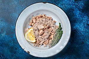 Canned Tuna chunks in olive oil ready for eat. Blue background. Top view