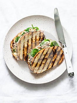 Canned tuna, mozzarella cheese, spinach hot sandwiches on a light background, top view. Delicious brunch, tapas, snack