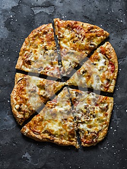 Canned tuna, tomatoes, mozzarella cheese puff pastry pizza on a dark background, top view. Delicious tapas, appetizers