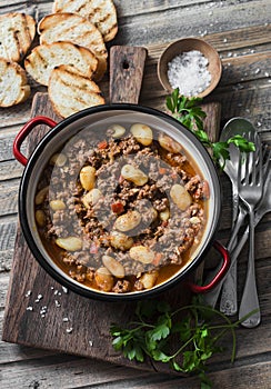 Cannellini beans beef slow-cooker stew on the wooden table, top view.