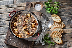 Cannellini beans beef slow-cooker stew on the wooden table, top view.