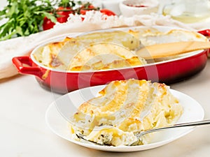 Cannelloni with filling of ricotta and parsley, baked with bÃ©chamel sauce, side view, white marble background