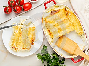 Cannelloni with filling of ricotta and parsley, baked with bÃ©chamel sauce, top view, white marble background