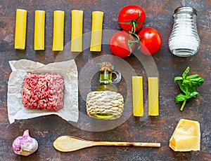 Cannelloni, tomatoes, minced meat and other ingredients. Dark background. Italian cuisine