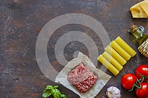Cannelloni, tomatoes, minced meat and other ingredients. Dark background. Italian cuisine