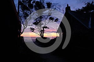 Cannon Beach at sunset: scenic orange, red and purple skies. House silhouettes