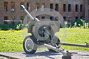 Cannon Second World War against the background of a destroyed red brick building